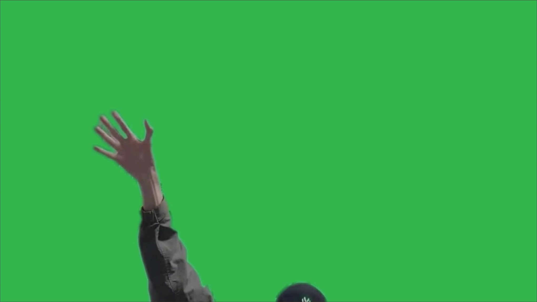 Filmed figure raising an arm against a green background